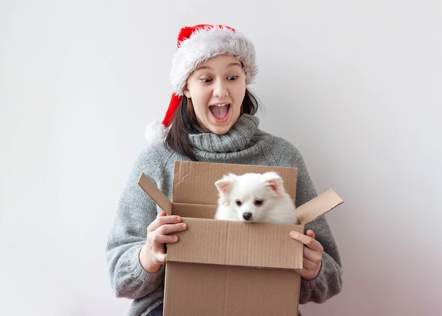Una adolescente abre una caja de cartón y hay un perrito pomerania.