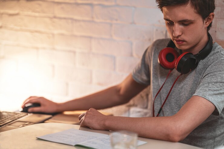 Foto adolescente activo con auriculares escucha conferencias, lo hace en una computadora portátil, usando una computadora portátil