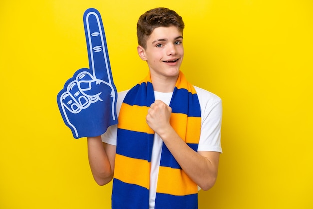 Foto adolescente aficionado a los deportes aislado de fondo amarillo celebrando una victoria