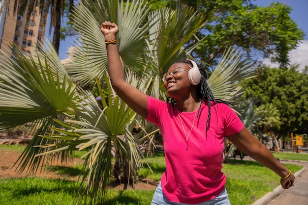 Adolescente africano bailando en el parque con auriculares