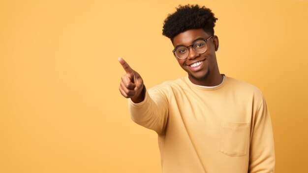 Adolescente africano feliz y sonriente señalando con los dedos a un lado presentando una nueva oferta promocional mostrando anuncios en el espacio de copia para comprar producto promocional de publicidad aislado en un fondo beige