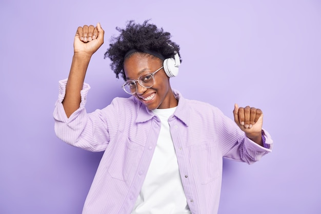 Adolescente afro-americana feliz com pele escura aprecia uma música popular em movimentos de aplicativos de áudio com ritmo de música