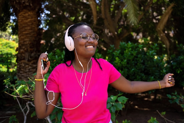 Adolescente afro-americano ouvindo música com fones de ouvido e celular