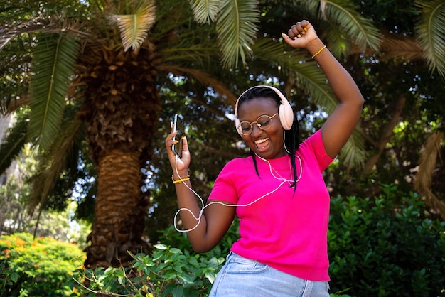 Adolescente afro-americano ouvindo música com fones de ouvido e celular