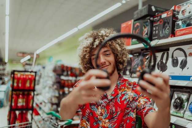 Un adolescente afro inspecciona y compra un auricular para computadora portátil en un gran centro comercial