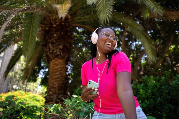 Adolescente afroamericano escuchando música con auriculares y móvil