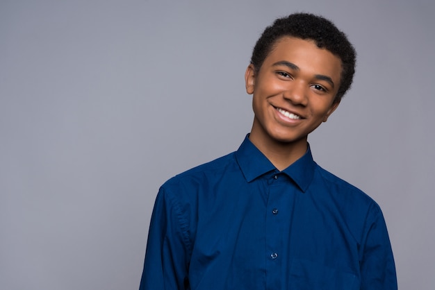 Adolescente afroamericano feliz en camisa de mezclilla.