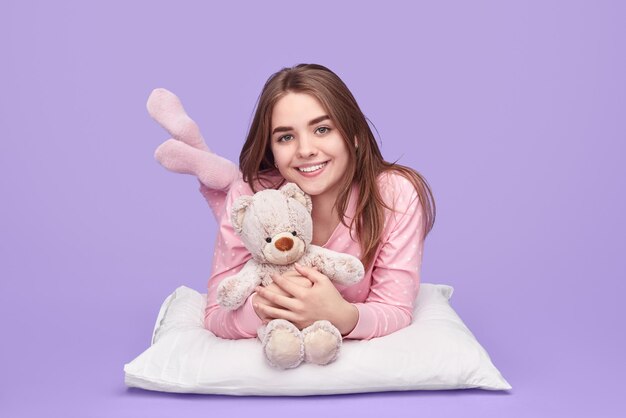 Adolescente alegre con juguete acostado en la almohada
