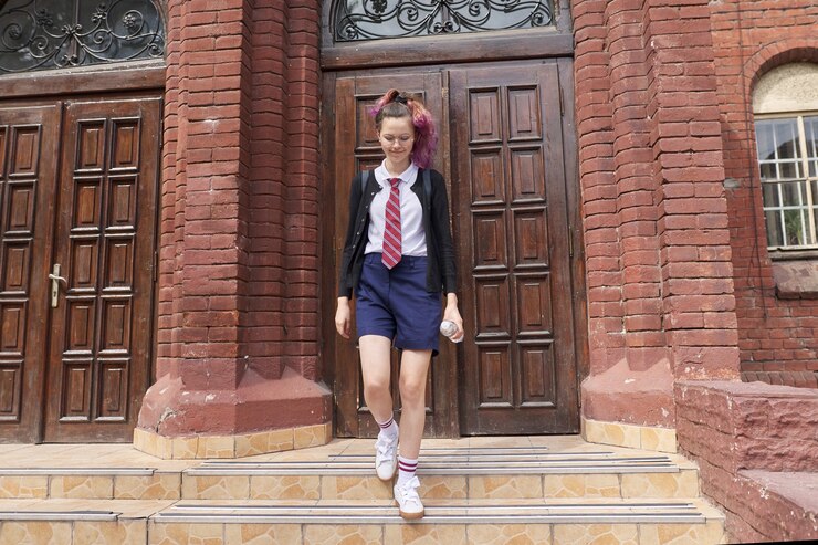 Foto adolescente aluna de uniforme com mochila, construindo o plano de fundo da escola. de volta às aulas, de volta à faculdade, educação, conceito de adolescentes