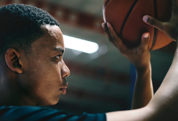 Adolescente americano africano concentrado em jogar basquete