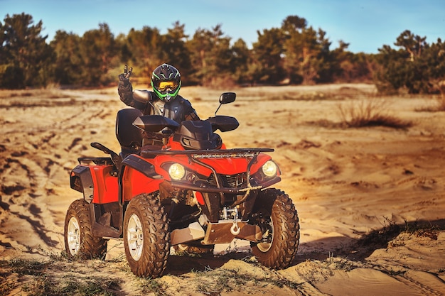 Adolescente andando de quadriciclo em dunas de areia fazendo uma curva na areia