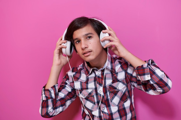 Adolescente árabe usando fones de ouvido e ouvindo música fundo rosa