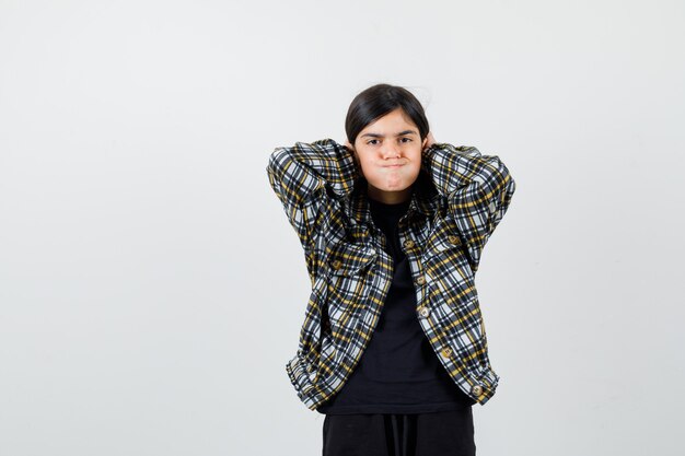 Adolescente arreglando su cabello en camisa casual y mirando molesto, vista frontal.