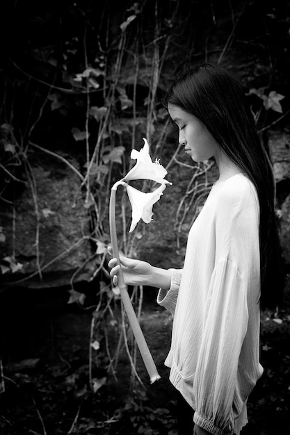 Foto adolescente asiática en blusa púrpura con flores blancas en sus manos vi