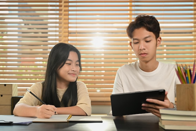 Adolescente asiática feliz fazendo casa trabalhando com tutor em casa conceito de educação em casa e aprendizagem