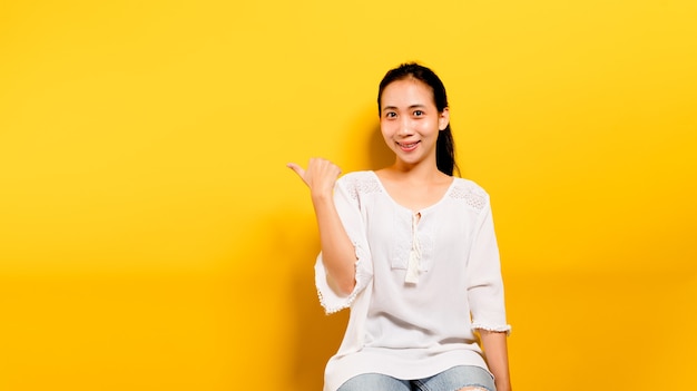 Adolescente asiática que se siente feliz. sonriendo y mirando a la cámara al tomar fotografías de sí mismo Fotografía de estudio amarilla Concepto de sonrisa, varias presentaciones, espacio libre