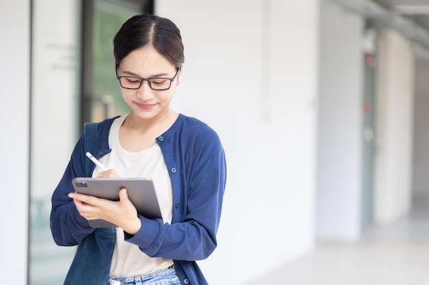Adolescente asiática universitária usando tablet online aprendendo estilo de vida educacional moderno no campus da escola