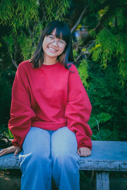 Adolescente asiático alegre usando óculos, sentado na mesa de madeira