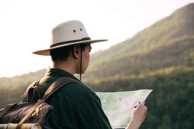 Adolescente asiático con brújula con mapa paoer para caminar a través del bosque hasta la cima de la montaña.