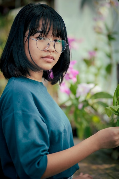 Adolescente asiático cuida de la planta de flor de orquídea en invernadero