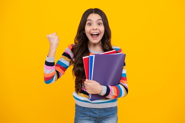 Adolescente asombrado Regreso a la escuela Colegiala adolescente con libro listo para aprender Niños de la escuela sobre fondo aislado de estudio amarillo