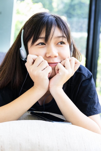 Adolescente con auriculares y escuchando música desde el teléfono móvil en casa