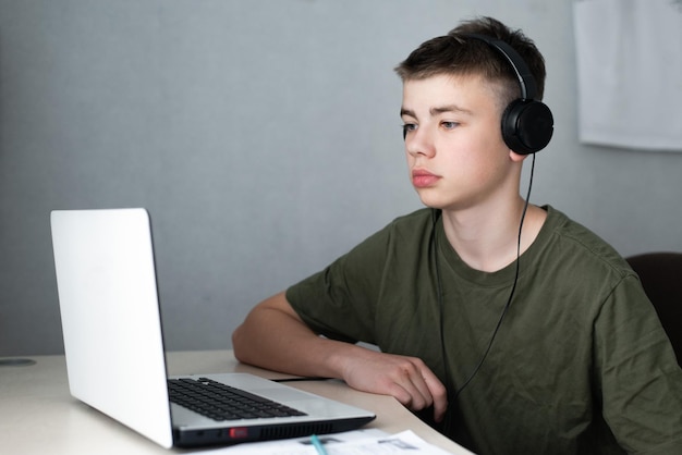 Adolescente con auriculares usando una computadora portátil para estudiar el concepto de educación en línea