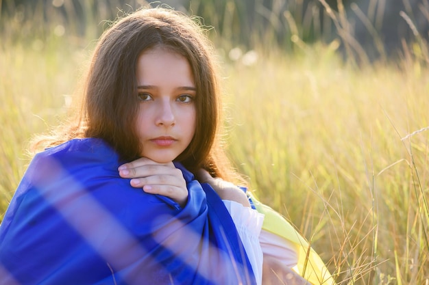 Una adolescente con una bandera ucraniana sobre sus hombros.