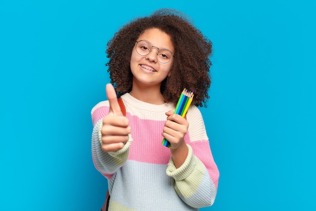 Foto adolescente bastante afro se sentindo orgulhoso, despreocupado, confiante e feliz, sorrindo positivamente com o polegar para cima