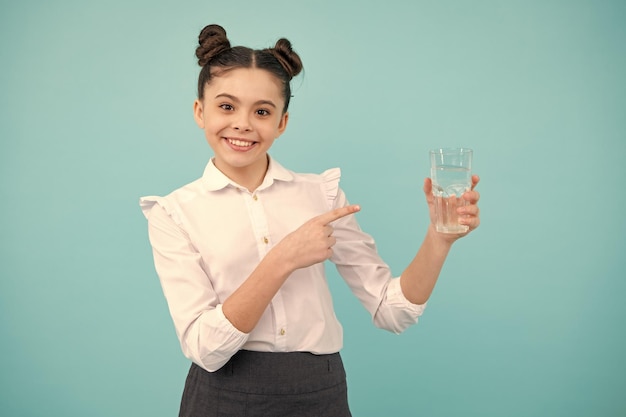 Adolescente bebendo água de vidro isolado em fundo azul Saúde da vida diária Adolescente feliz, emoções positivas e sorridentes de adolescente