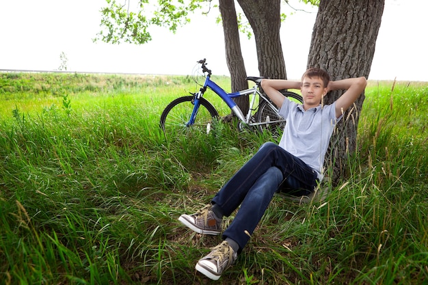 Un adolescente con una bicicleta en el parque sobre el césped