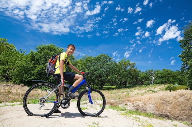 Un adolescente en bicicleta viajando en el bosque.