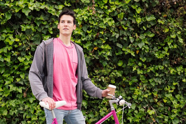 Adolescente con una bicicleta vintage sobre fondo de plantas