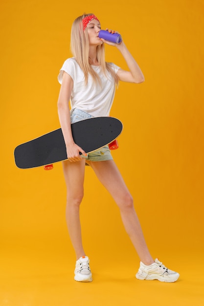 Adolescente bonita e moda, posando com um skate no estúdio