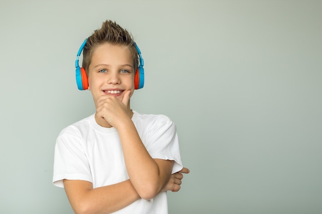 Adolescente bonito e sorridente com uma camiseta ouve música com fones de ouvido sem fio