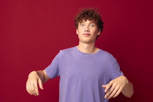 Adolescente bonito em camisetas roxas posando emoções fundo vermelho inalterado