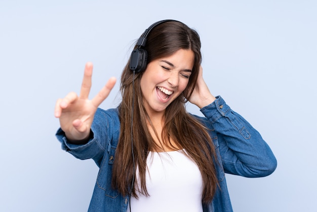 Adolescente brasileña escuchando música y cantando sobre fondo azul aislado