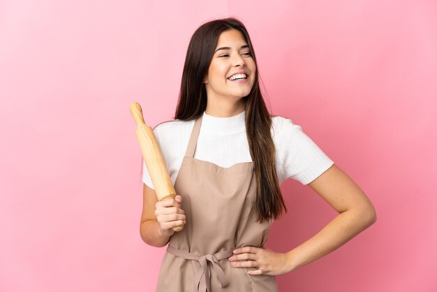 Adolescente brasileña sosteniendo un rodillo aislado posando con los brazos en la cadera y sonriendo