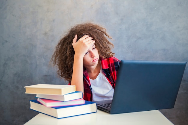 Adolescente de cabello rizado gitl websurfing internet en la computadora portátil en casa