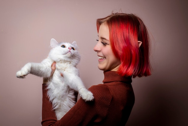 Adolescente con cabello rosado sosteniendo un gato blanco en sus brazos