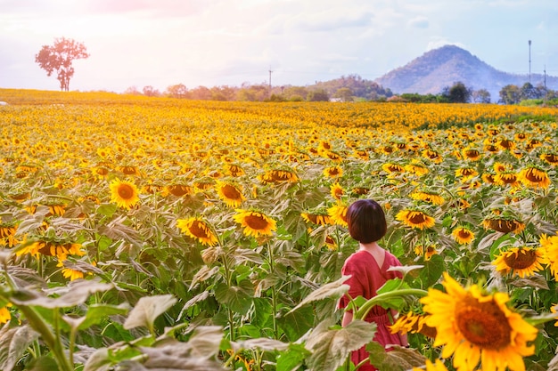 Adolescente con campo de girasoles en el atardecer, personas con paisaje