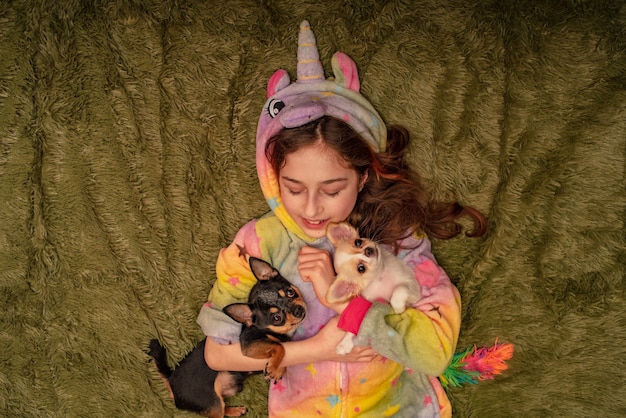 Adolescente en casa en pijama en una tela escocesa verde con un cachorro de Chihuahua blanco y un Chihuahua negro.