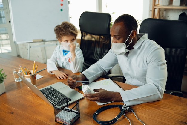 Adolescente caucasiano como um médico, consultando, dando recomendações, tratando. Pequeno médico durante a discussão, estudando com o colega mais velho. Conceito de infância, emoções humanas, saúde, medicina.