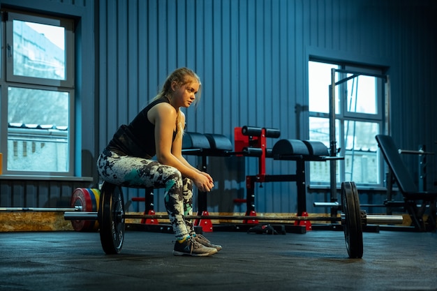 Adolescente caucásica practicando levantamiento de pesas en el gimnasio