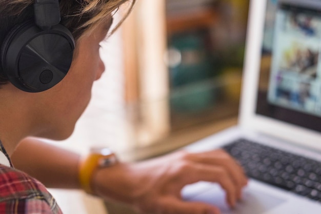 Foto adolescente caucásico enfocado en sus tareas con su computadora portátil tipo milenario trabajando solo