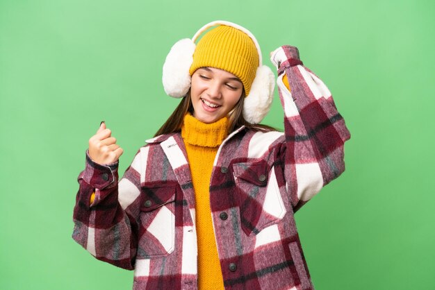 Adolescente chica caucásica vistiendo manguitos de invierno sobre antecedentes aislados celebrando una victoria