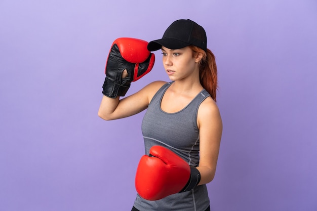 Adolescente chica rusa aislada en la pared púrpura con guantes de boxeo