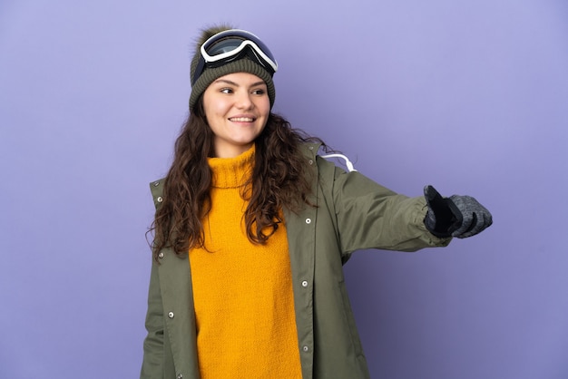 Foto adolescente chica rusa con gafas de snowboard aislado sobre fondo púrpura dando un pulgar hacia arriba gesto