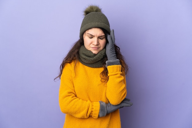 Adolescente chica rusa con sombrero de invierno aislado sobre fondo púrpura con dolor de cabeza