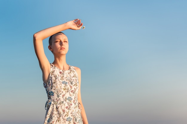 Adolescente chica en un vestido con un corte de pelo corto de pie mirando a lo lejos